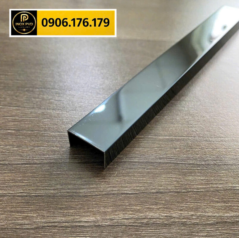 Thanh nẹp inox chữ U màu xám bạc đặt trên nền gỗ, ứng dụng xử lý mép gạch và cạnh vật liệu